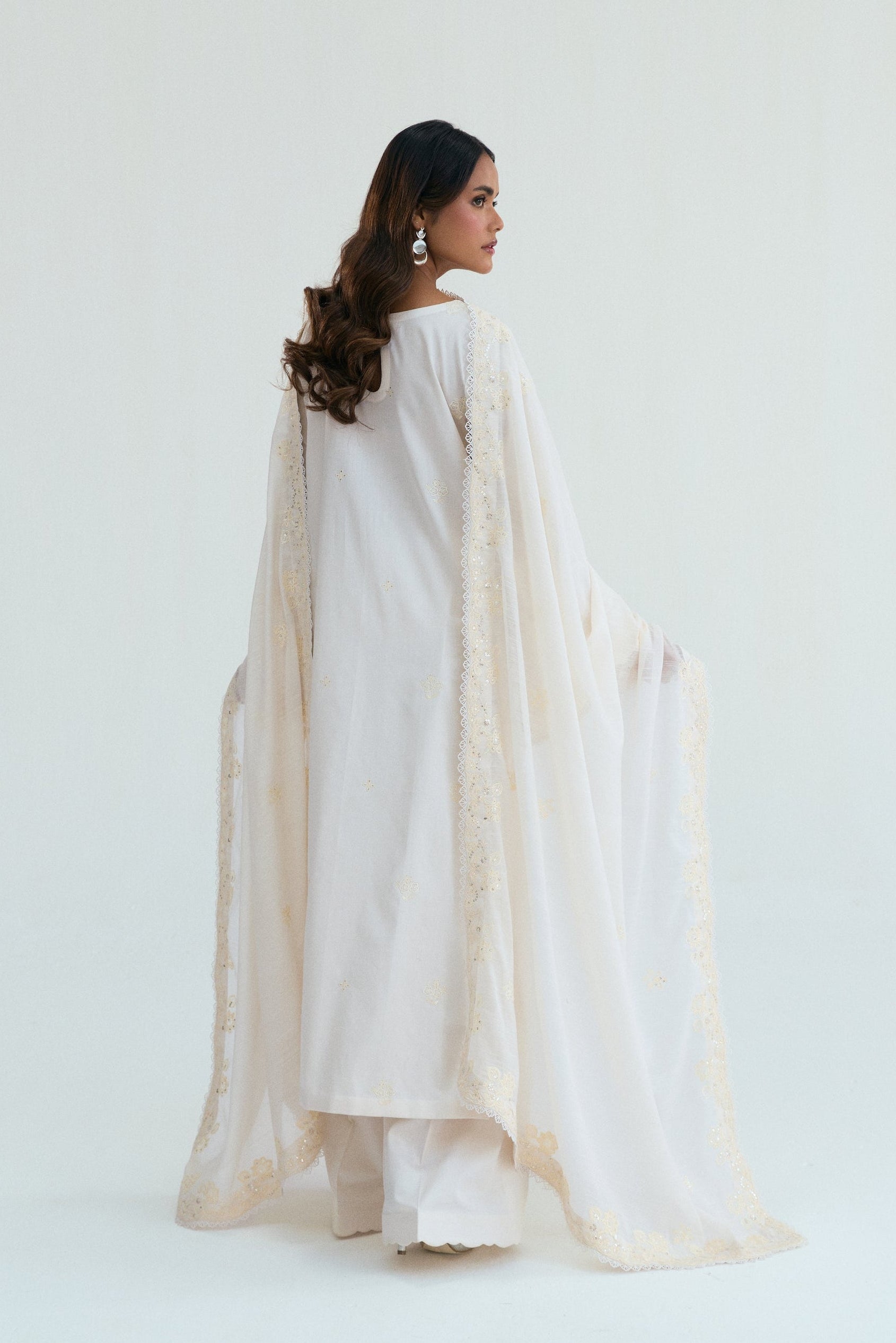  Ivory embroidered outfit with scalloped detailing, long izaar trousers,and sequin dupatta. Ideal for Eid, iftar parties and formal occasions.