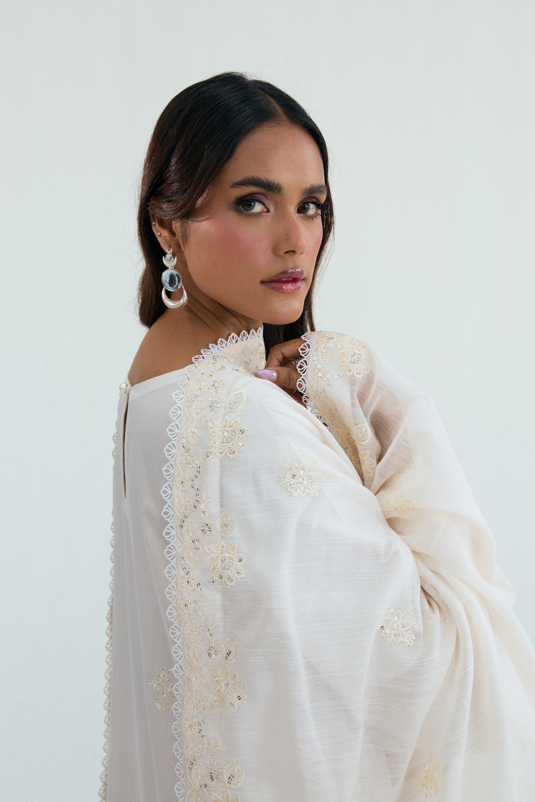  Ivory embroidered outfit with scalloped detailing, long izaar trousers,and sequin dupatta. Ideal for Eid, iftar parties and formal occasions.