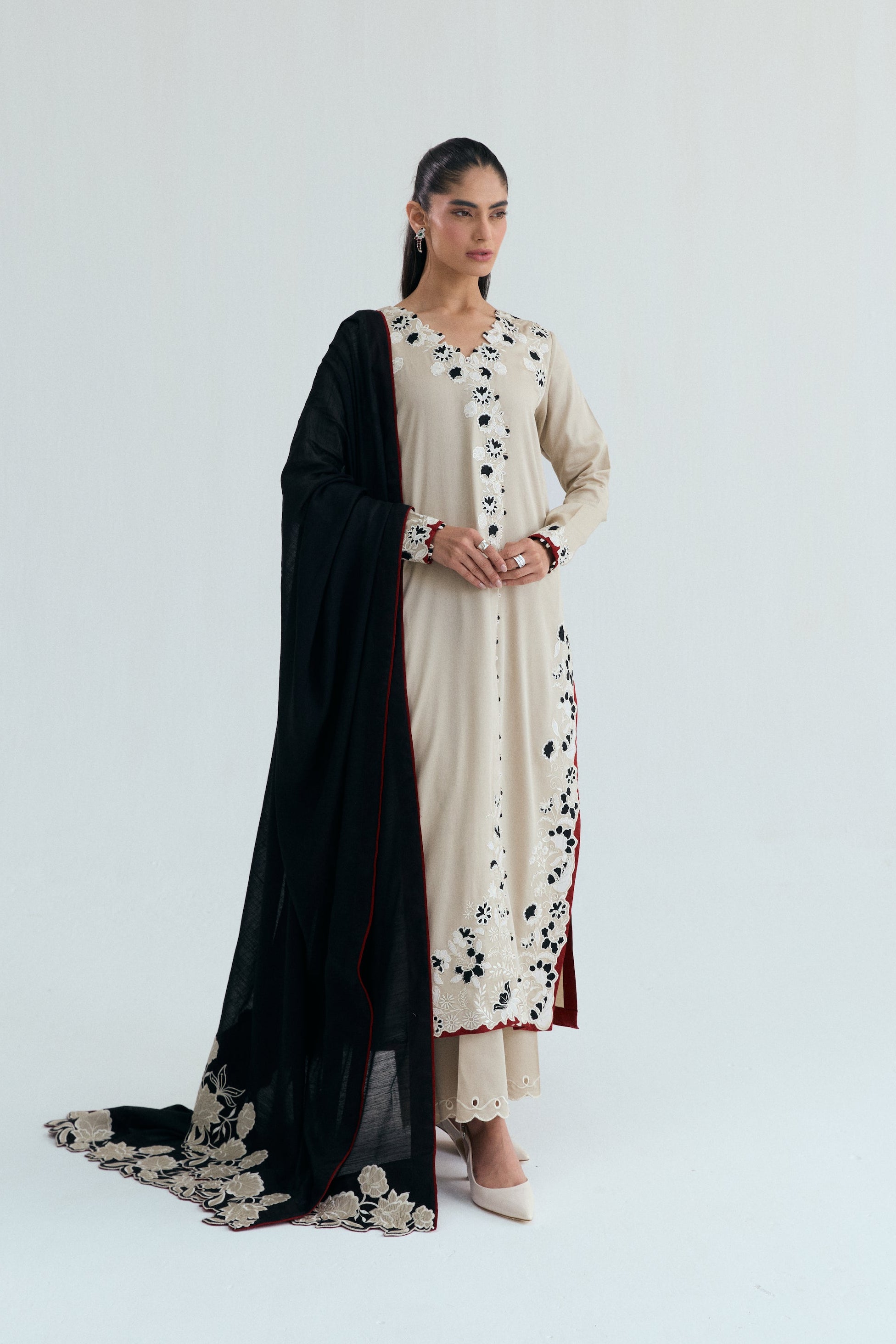 Ivory embroidered Pakistani outfit with asymmetrical long shirt, wide-hem trousers, and black and white embroidered dupatta. Perfect for Eid, casual and formal events.