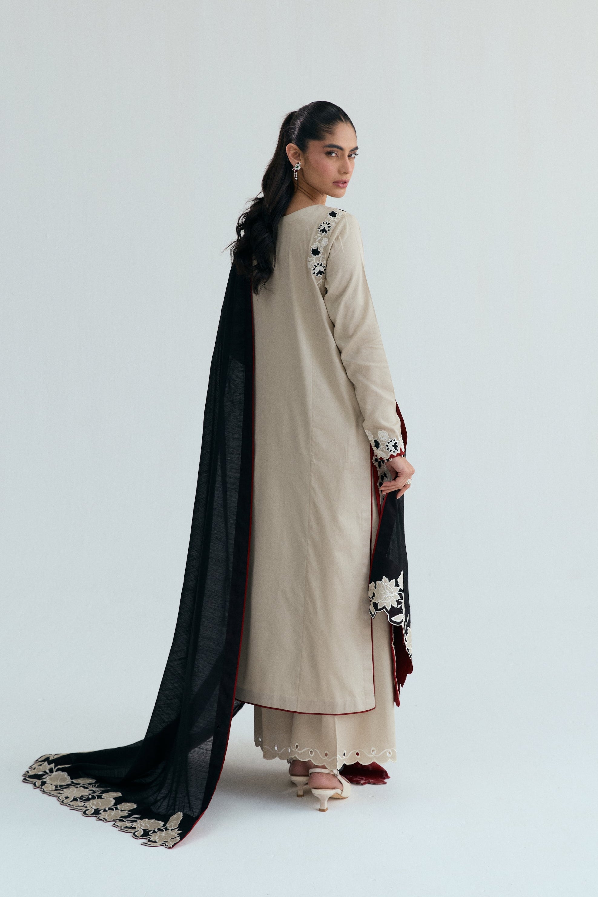 Ivory embroidered Pakistani outfit with asymmetrical long shirt, wide-hem trousers, and black and white embroidered dupatta. Perfect for Eid, casual and formal events.