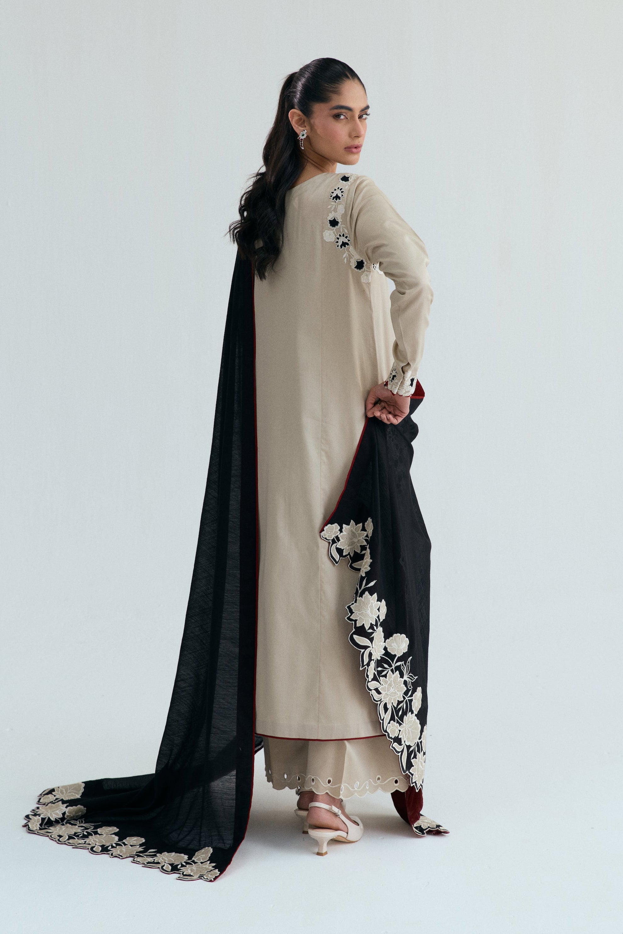 Ivory embroidered Pakistani outfit with asymmetrical long shirt, wide-hem trousers, and black and white embroidered dupatta. Perfect for Eid, casual and formal events.