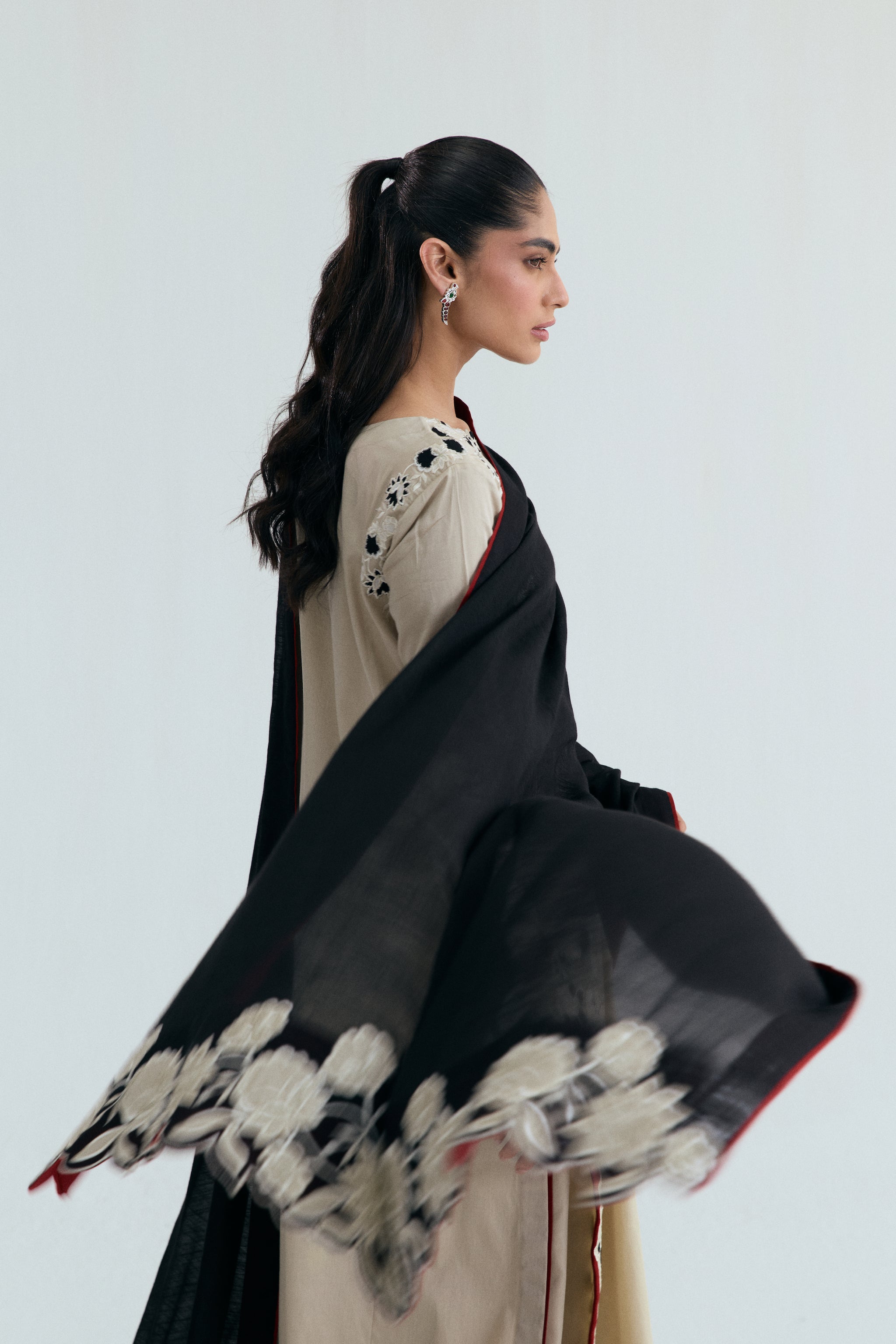Ivory embroidered Pakistani outfit with asymmetrical long shirt, wide-hem trousers, and black and white embroidered dupatta. Perfect for Eid, casual and formal events.