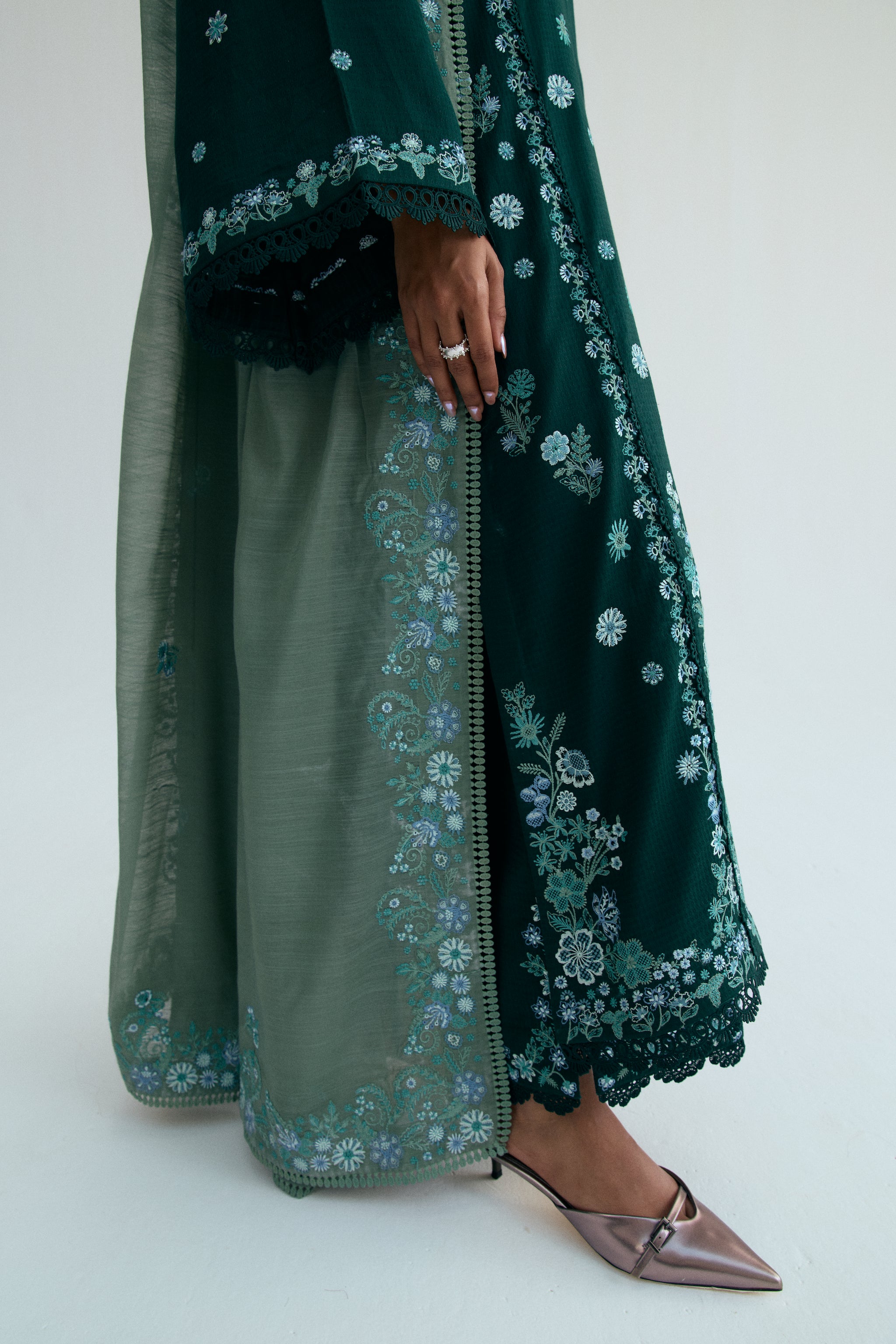 Deep green Pakistani three piece outfit with embroidered long shirt, lace-detailed izaar trousers, and contrasting pastel dupatta. Perfect for Eid.
