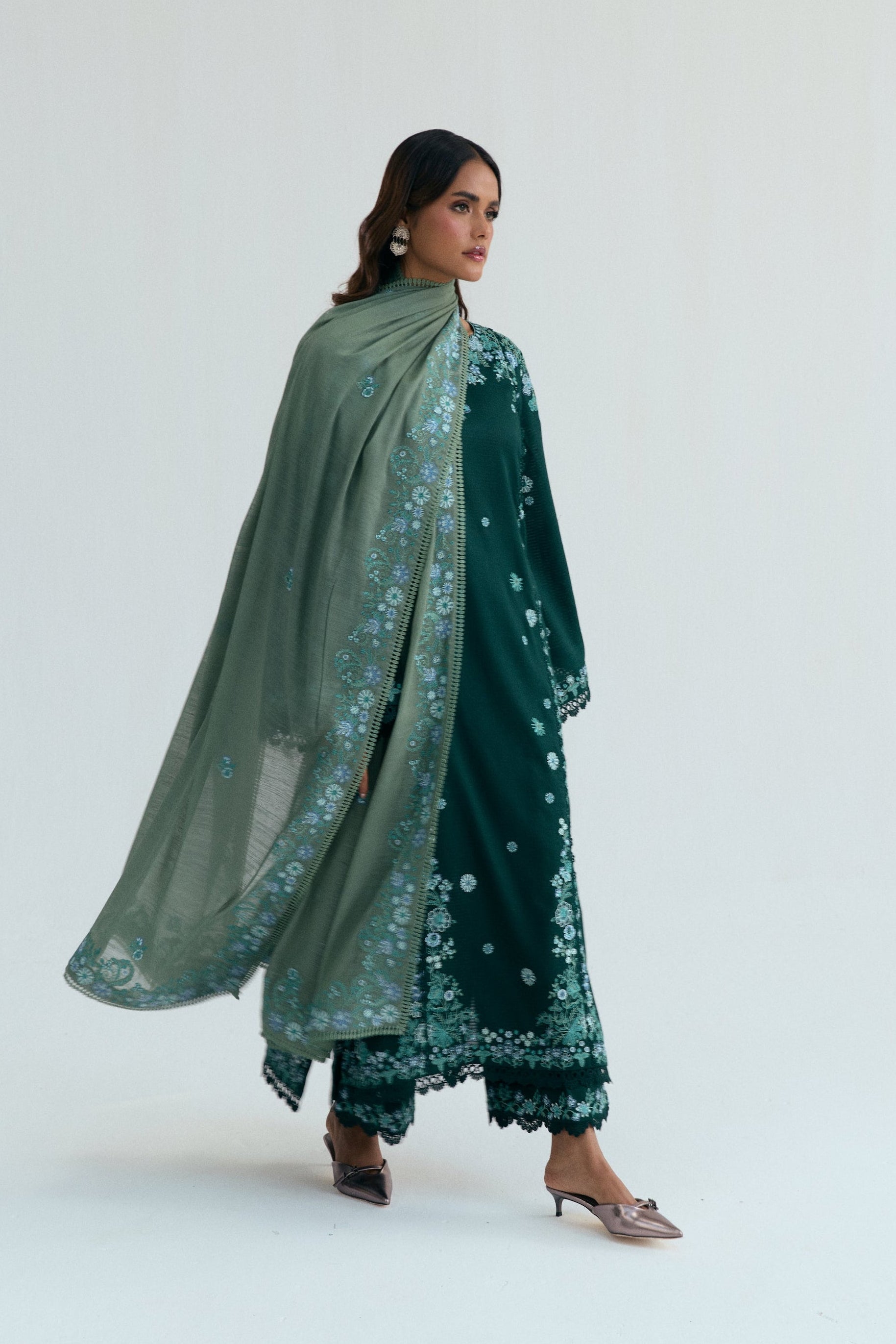 Deep green Pakistani three piece outfit with embroidered long shirt, lace-detailed izaar trousers, and contrasting pastel dupatta. Perfect for Eid.