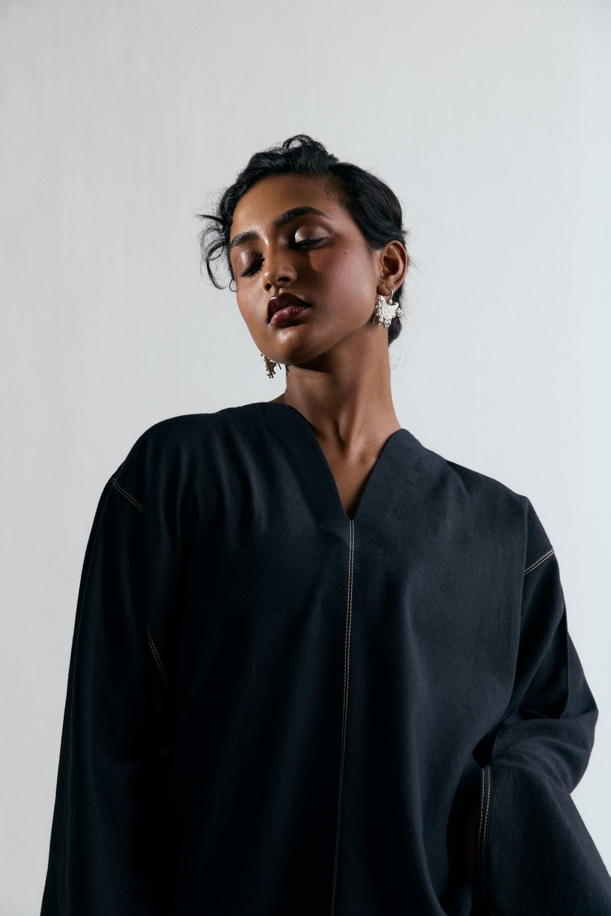 Close-up of structured V-neckline with contrast centre-front stitching on a black linen-cotton kaftan