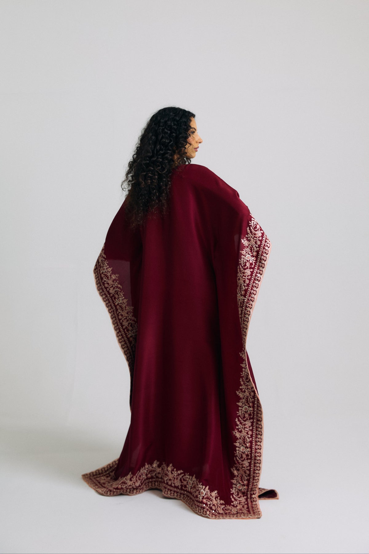 Back view of burgundy kaftan with plain back, embroidered sleeve borders and floral hem border