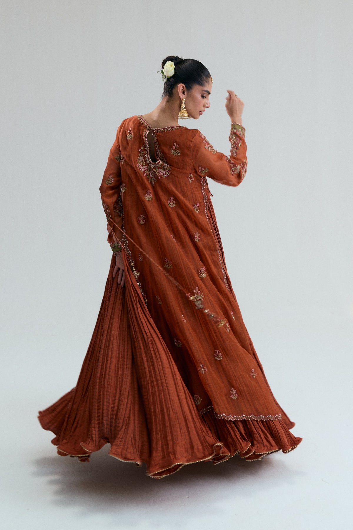 Burnt orange Pakistani suit shown mid-twirl, highlighting the high-flare crushed inner
