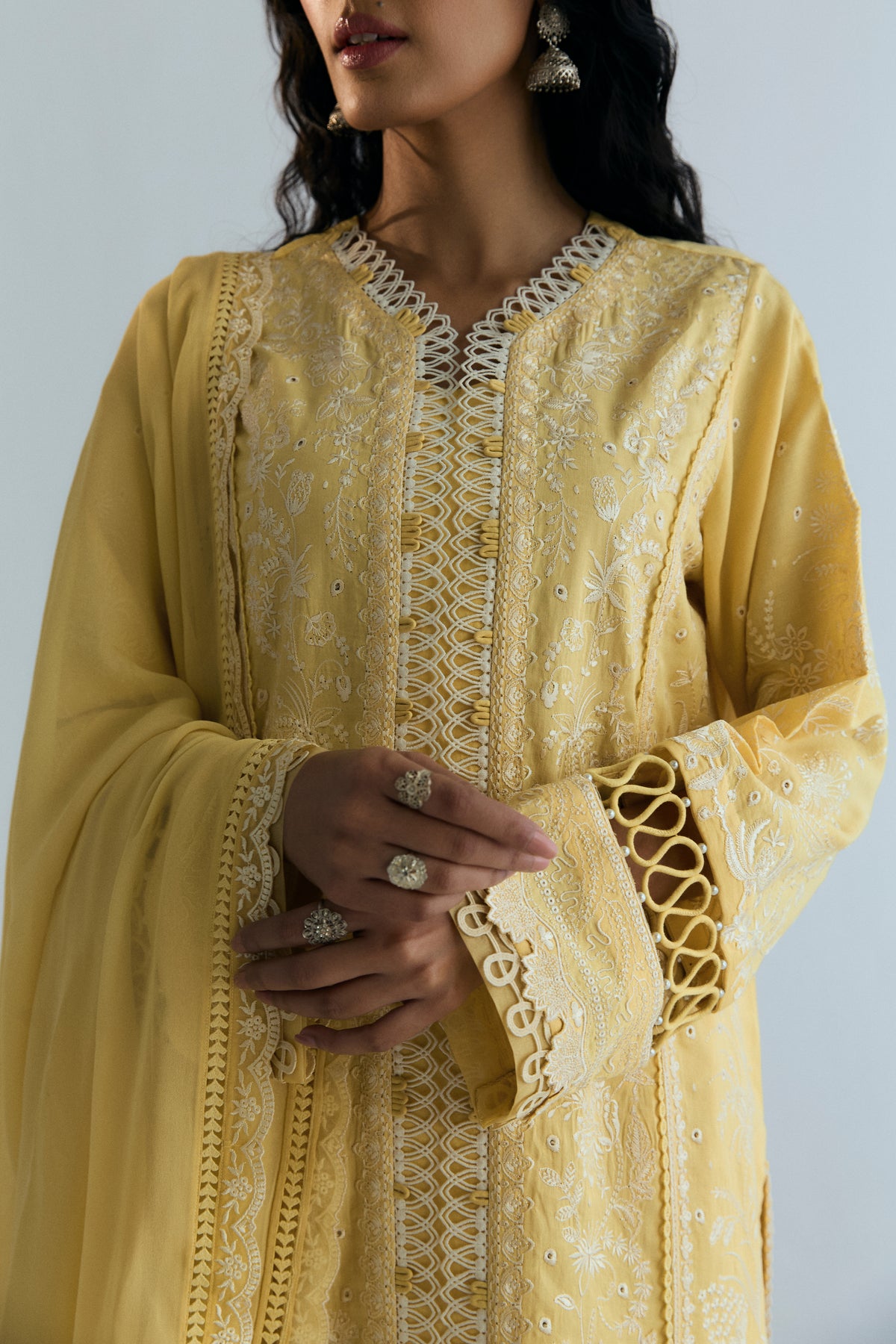 Close-up of V-neckline with ivory loop lace trim and embroidery on a butter yellow kameez