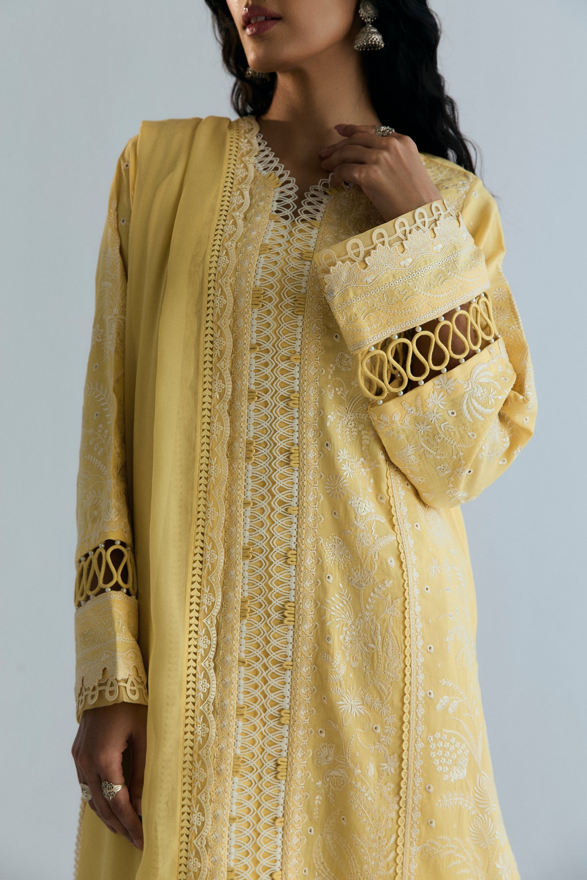 Embroidered sleeve cuff with looped detailing and V-neckline lace on a butter yellow Pakistani outfit