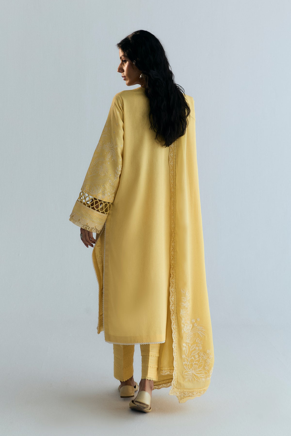 Back view of butter yellow Pakistani suit with plain kameez back, embroidered sleeve and floral dupatta corner