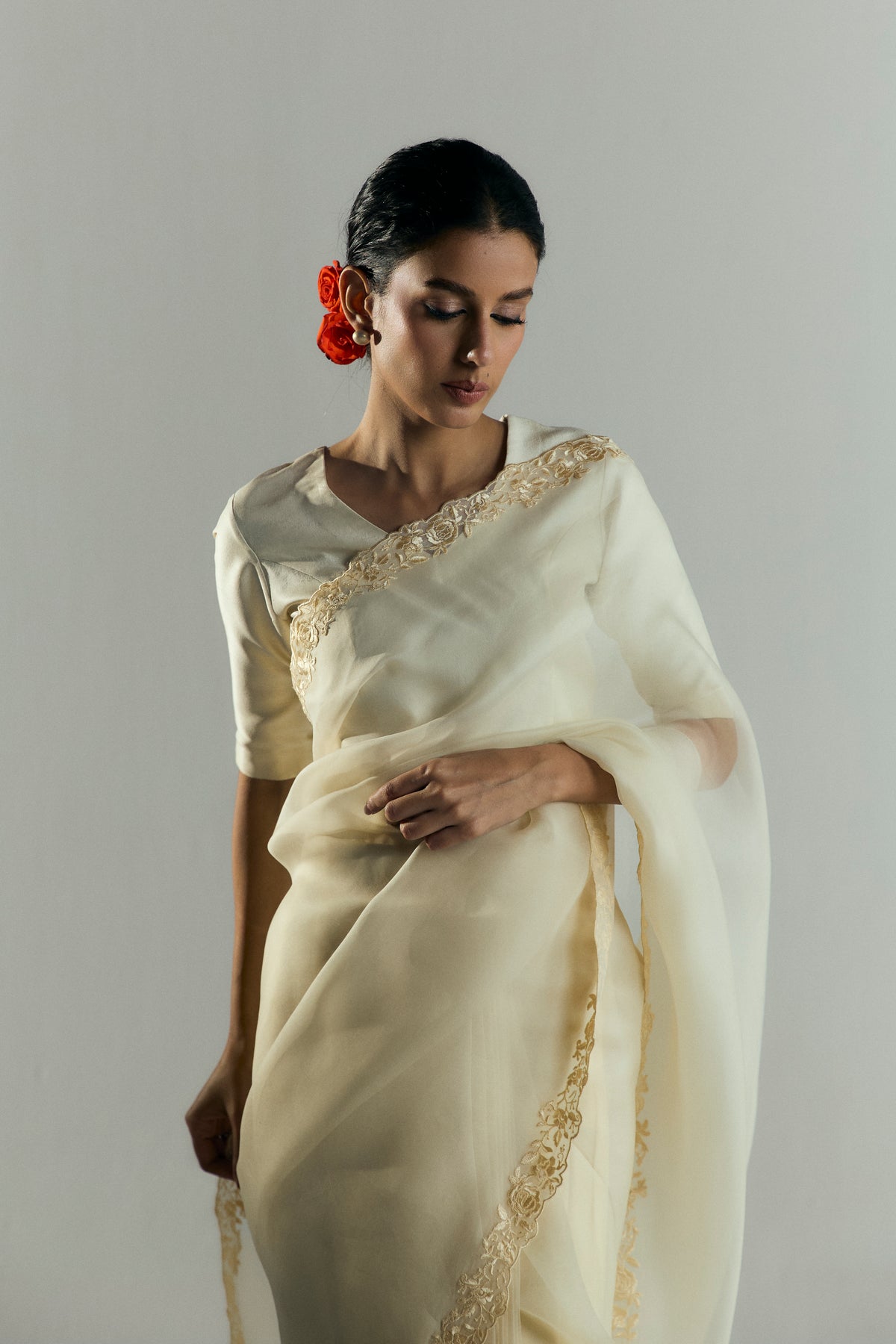 Close-up of the organza saree's gold floral embroidered border of an organza saree draped over a silk blouse.