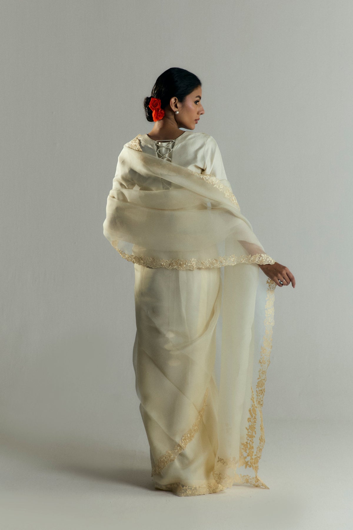 Back view of the chantilly-coloured sari set, highlighting a silk blouse that ties at the back and an embroidered saree pallu draped over the shoulders.