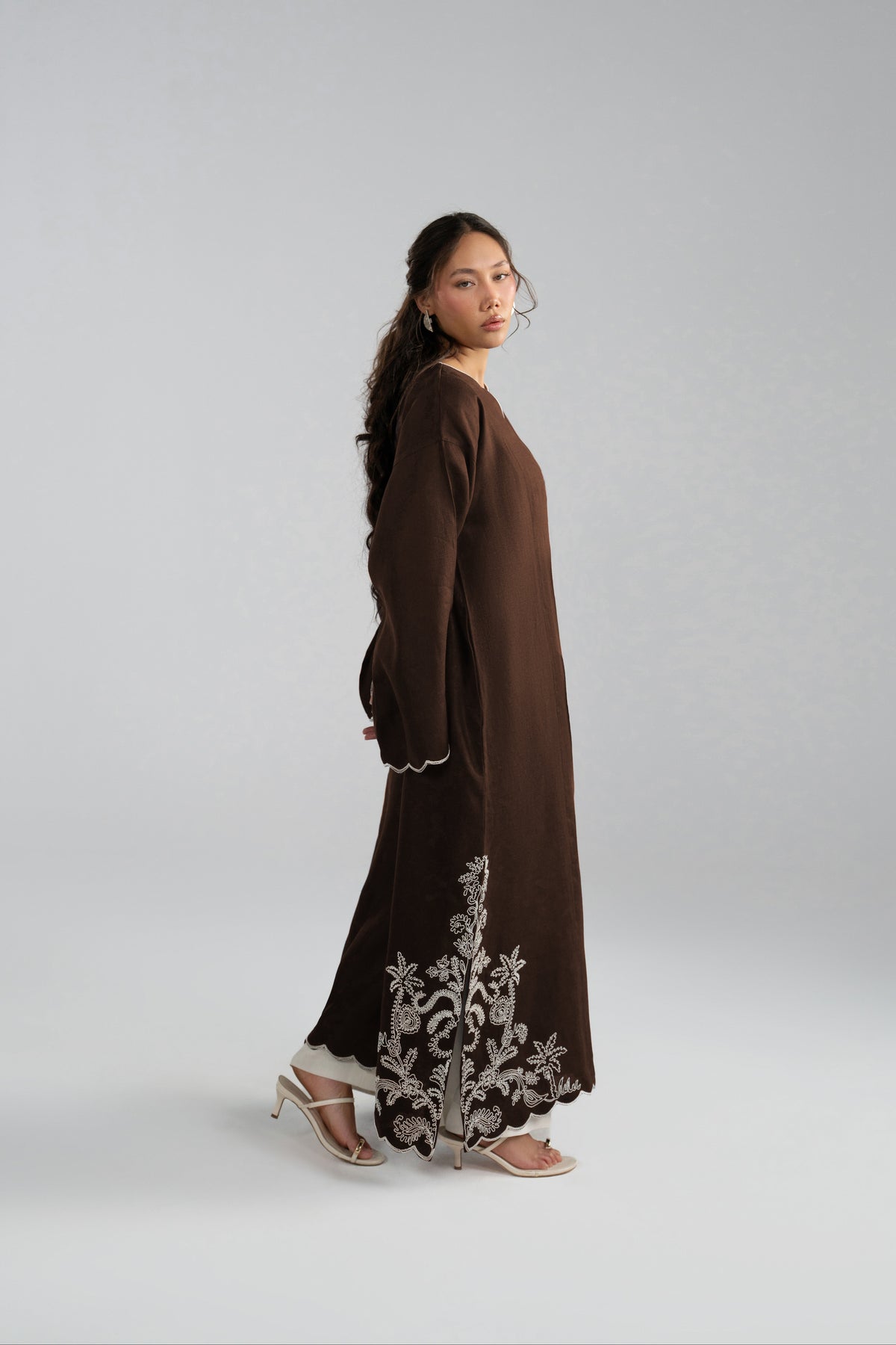 Linen woman long brown tunic dress with white embroidered floral patterns near the hem.