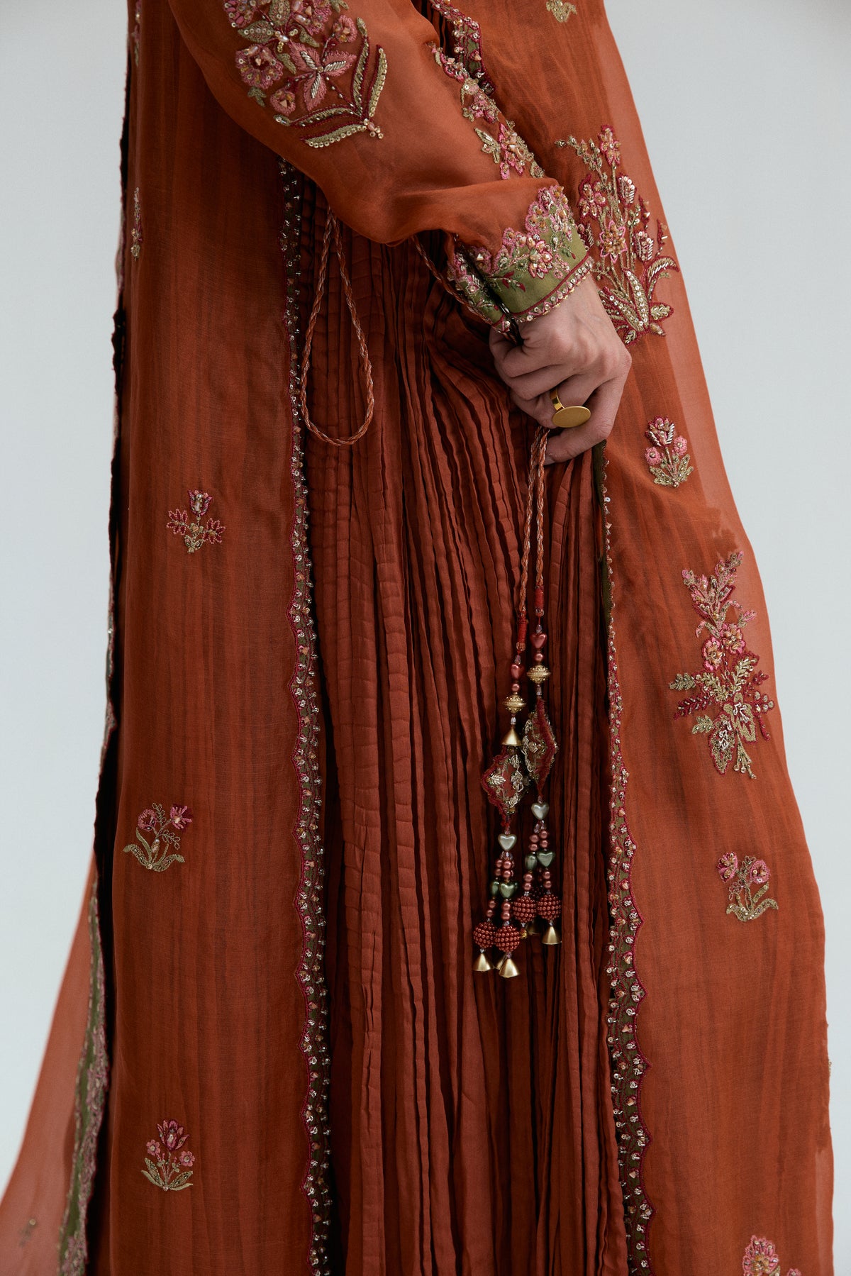Close-up of the crushed skirt inner's gota lace trim, held alongside a hand-beaded tassel