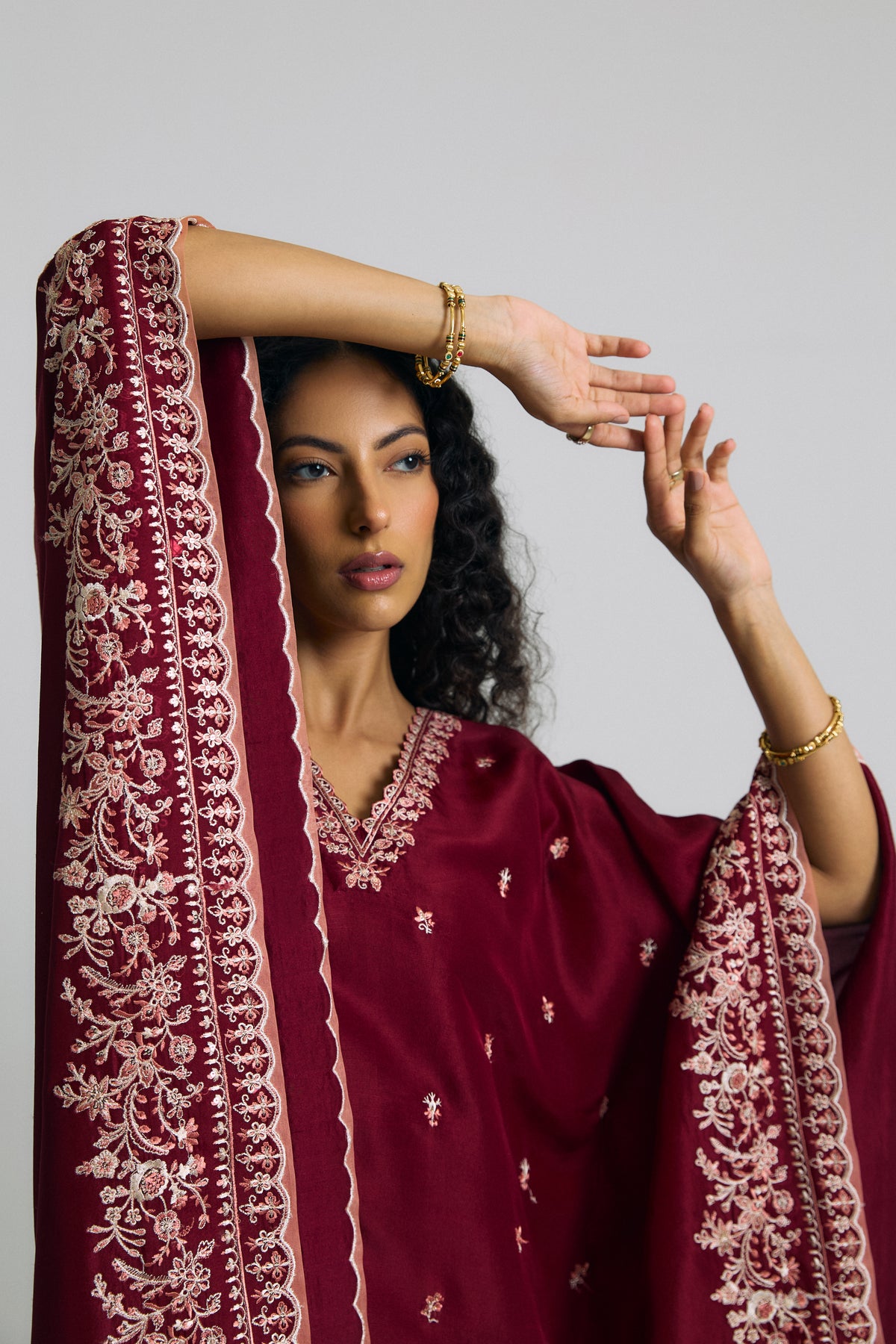 Embroidered kaftan sleeve raised to show floral border with peach scalloped edge beside the petal-edged neckline