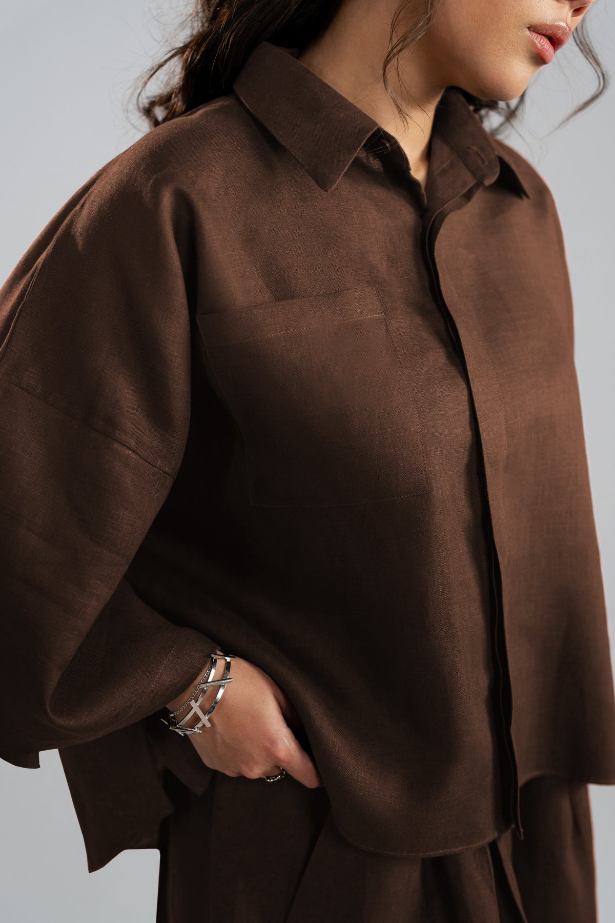 Close-up detail of an espresso brown button-up shirt featuring woven fabric texture, a pointed collar and a chest pocket.
