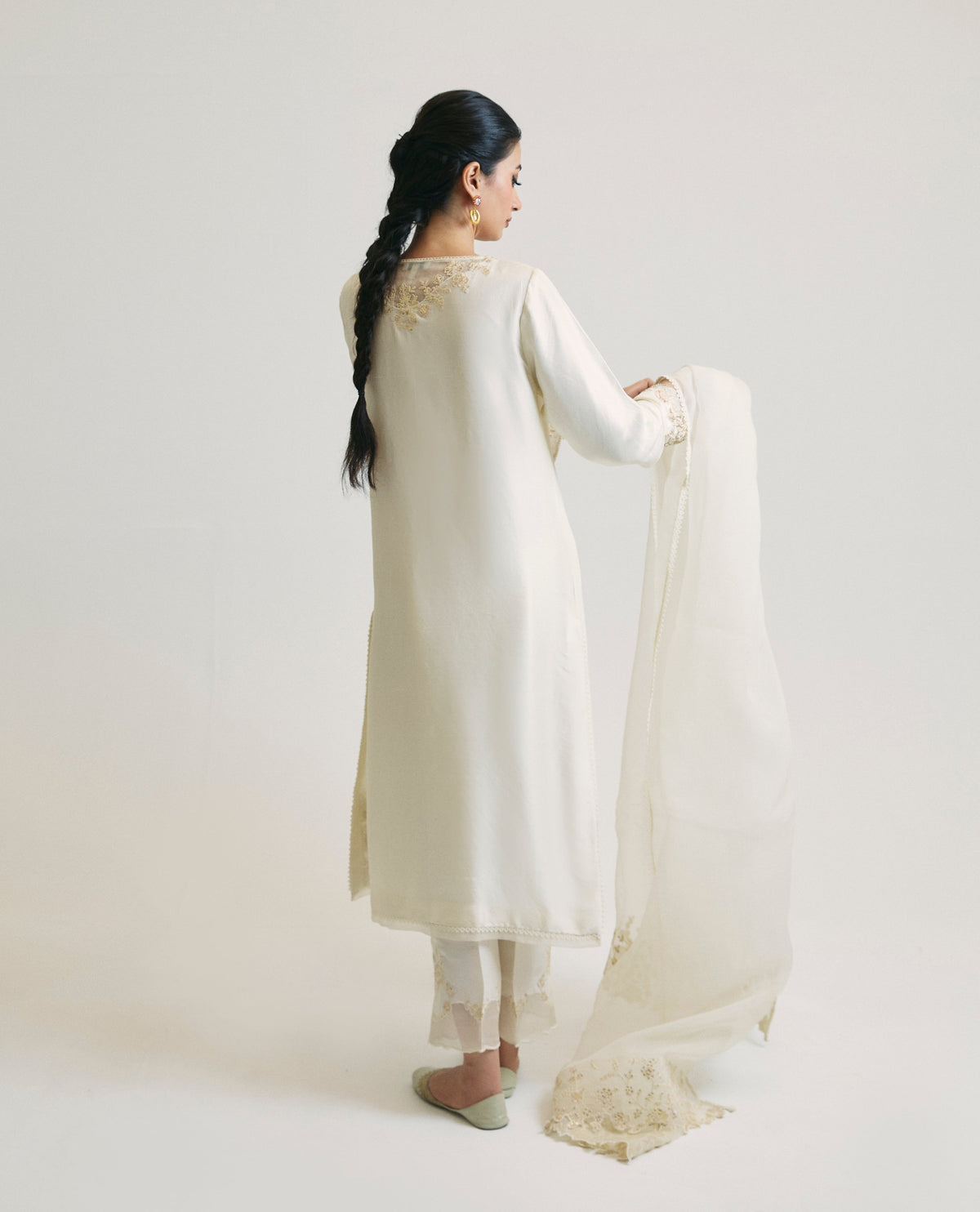 Back view of the ivory kameez, highlighting embroidery details across the shoulders of the otherwise plain back, alongside a floral-embroidered organza dupatta draped loosely to the side.