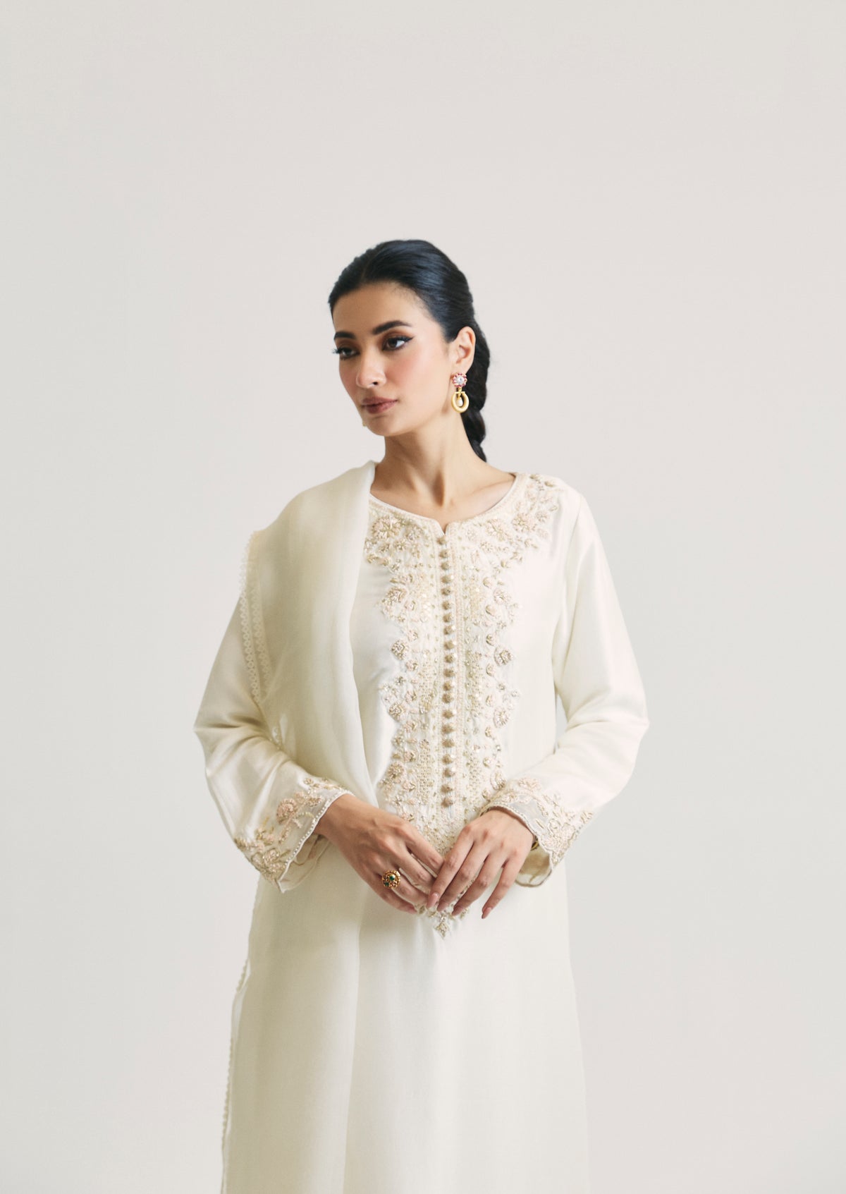 Upper-body shot of the ivory Pakistani suit, highlighting an organza dupatta draped over the shoulder, hand-embroidered floral detailing at the neckline and the details of the sleeve cuffs.