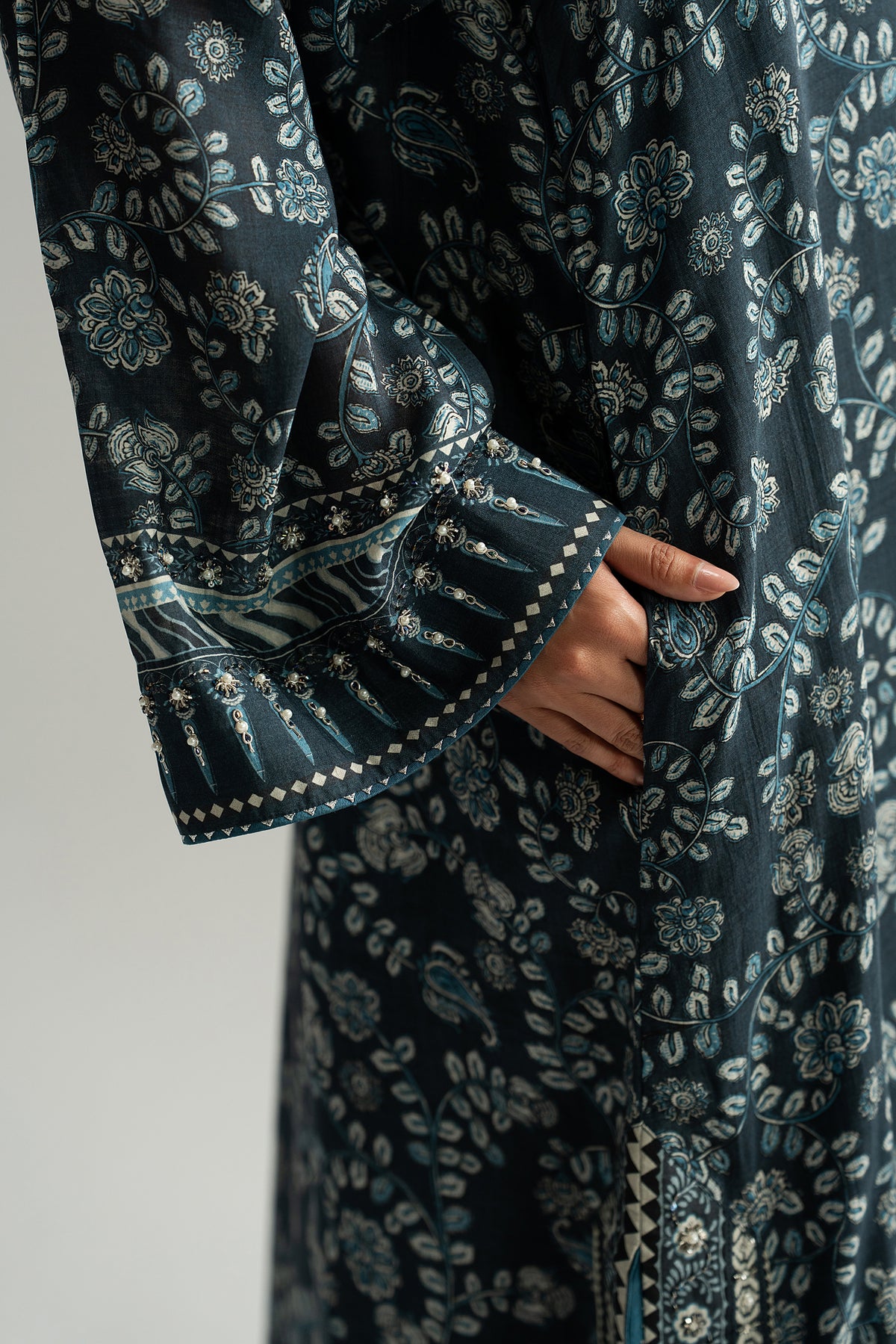 Detail of hand-stitched embellished cuff and floral print on the navy phiran sleeve