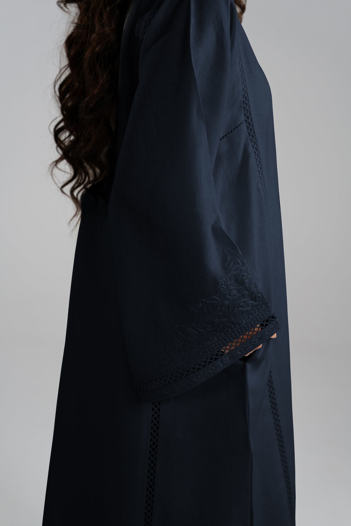 Close-up side view of a dark navy linen salwar kameez with embroidered lace detailing on the sleeve and side seams.