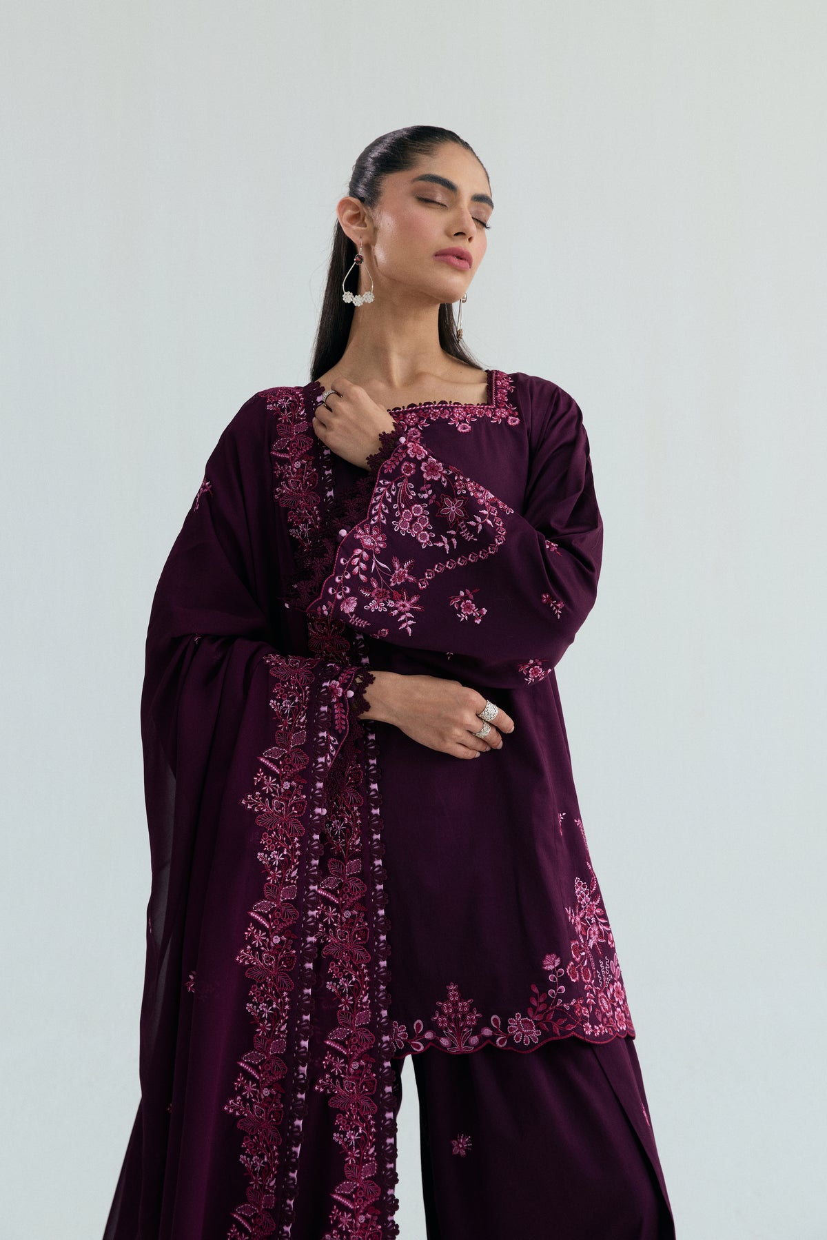 Close-up of the square neckline and pink floral embroidery bordering the plum kameez