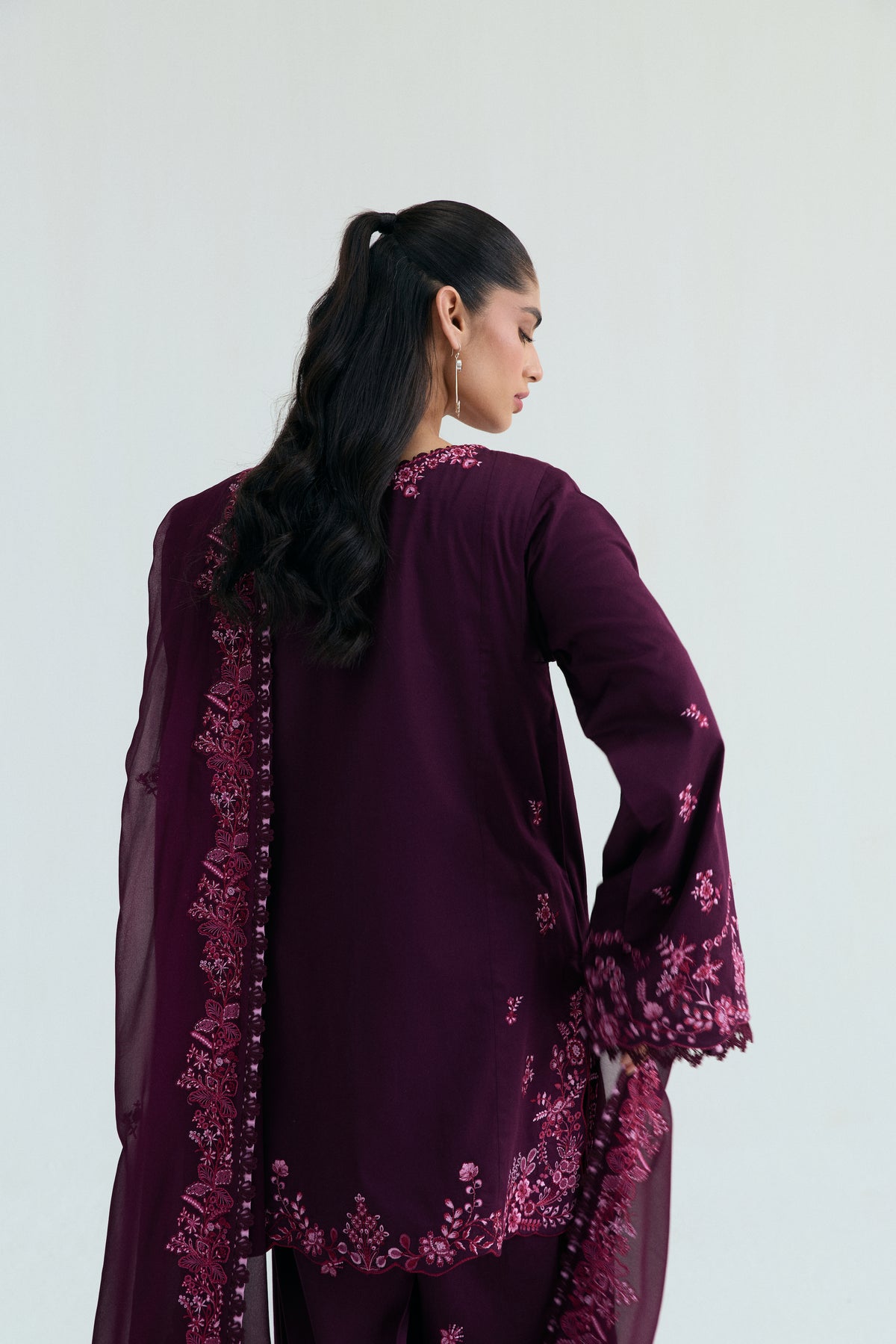 Close-up view of the back of a deep plum-colored Pakistani outfit, highlighting the embroidered cuff and the style of the dupatta.
