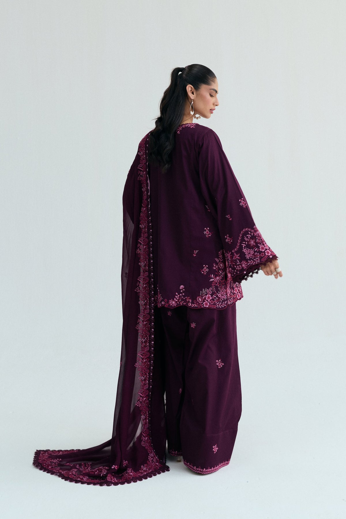 Back view of a deep purple (plum-colored) shalwar kameez, featuring an embroidered dupatta draped downwards along the length.