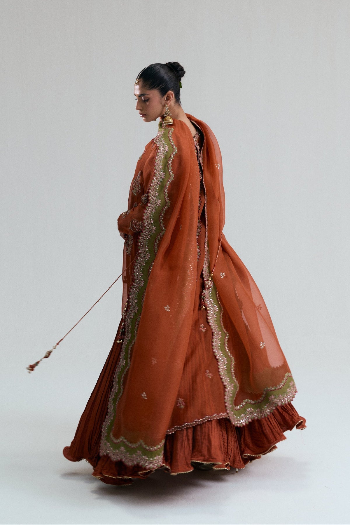 Rust organza dupatta with a scalloped olive-green border, draped over the shoulder from the back