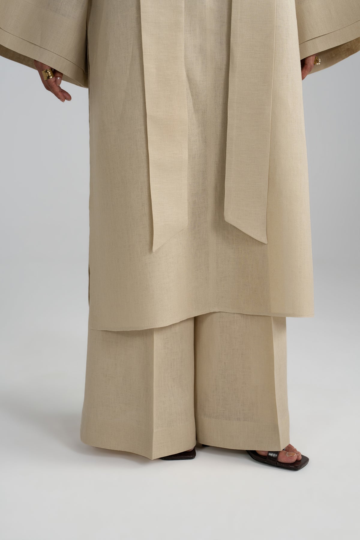 Close-up of the wide-leg linen trousers and hanging scarf tie, finished with black sandals