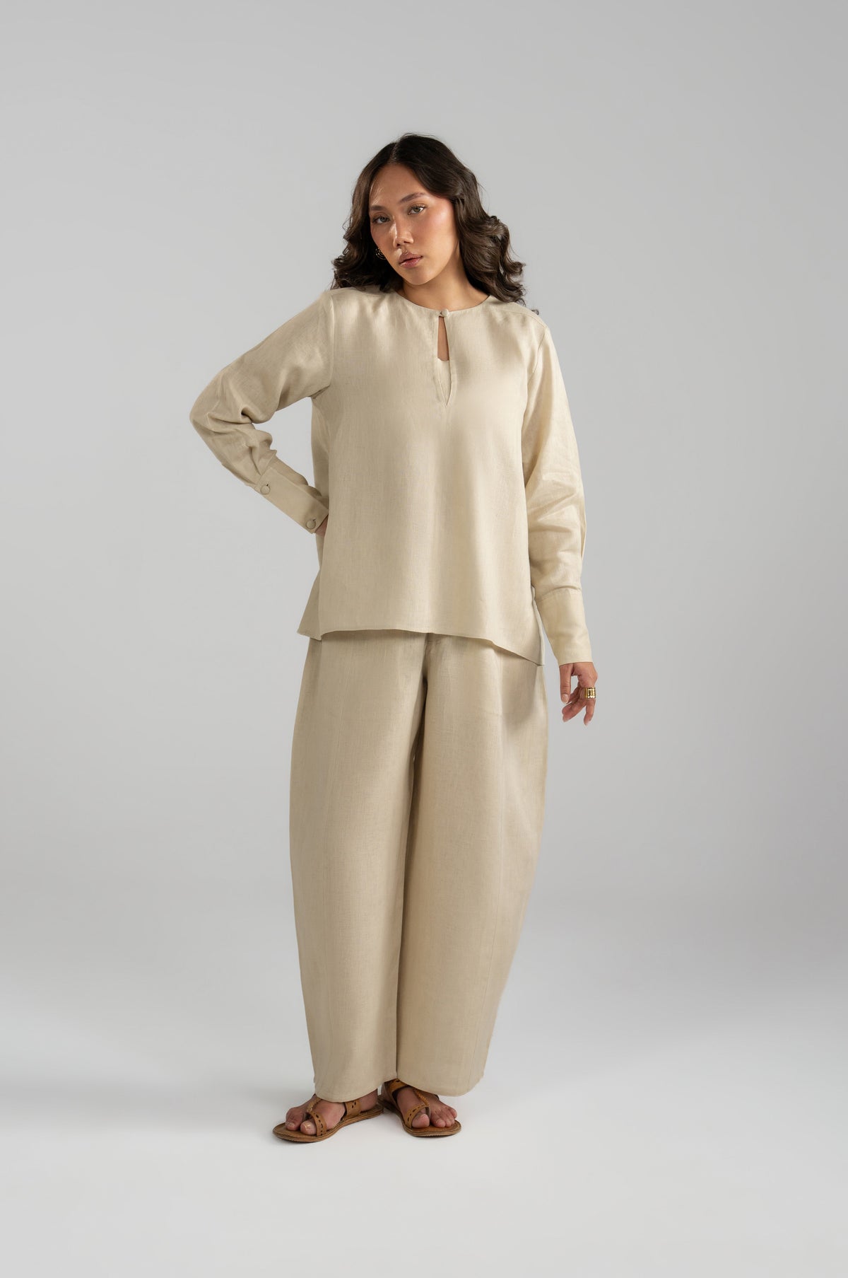 Full-length of Tuscany pure linen beige set featuring a keyhole neckline short shirt and wide panelled balloon trousers.