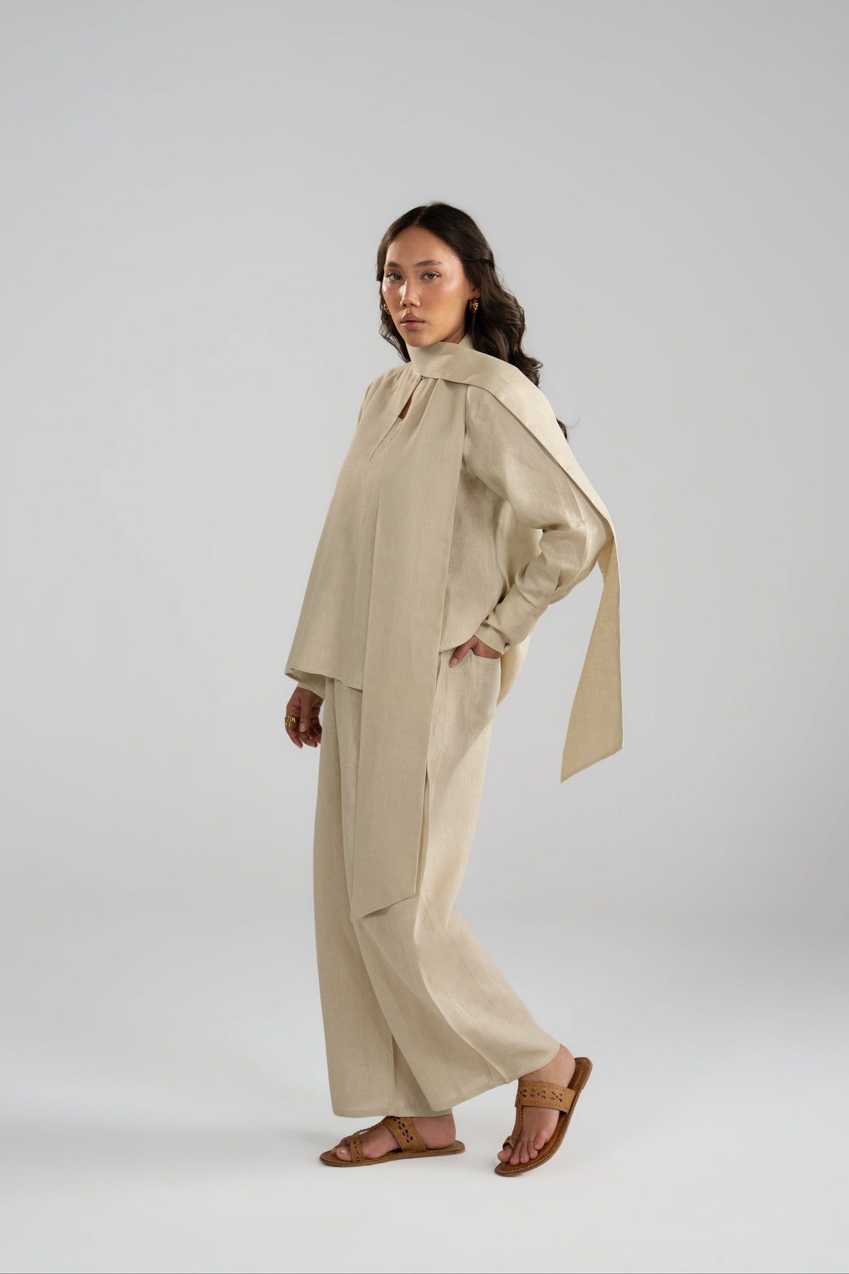 Side angle of Tuscany beige pure linen set featuring the matching short scarf accessory, keyhole tunic and balloon trousers.