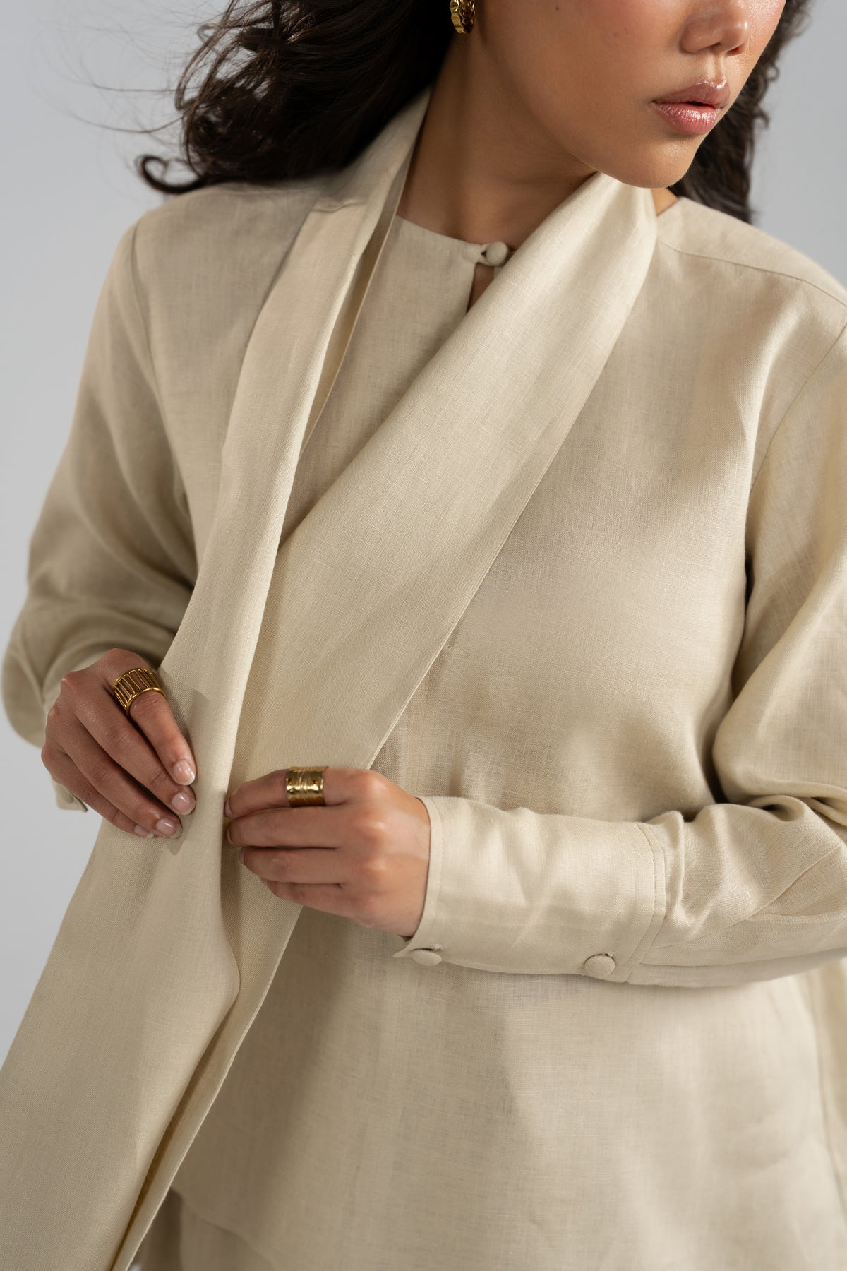Beige pure linen set, showing the woven fabric texture, buttoned cuffs, keyhole loop, and draped scarf.