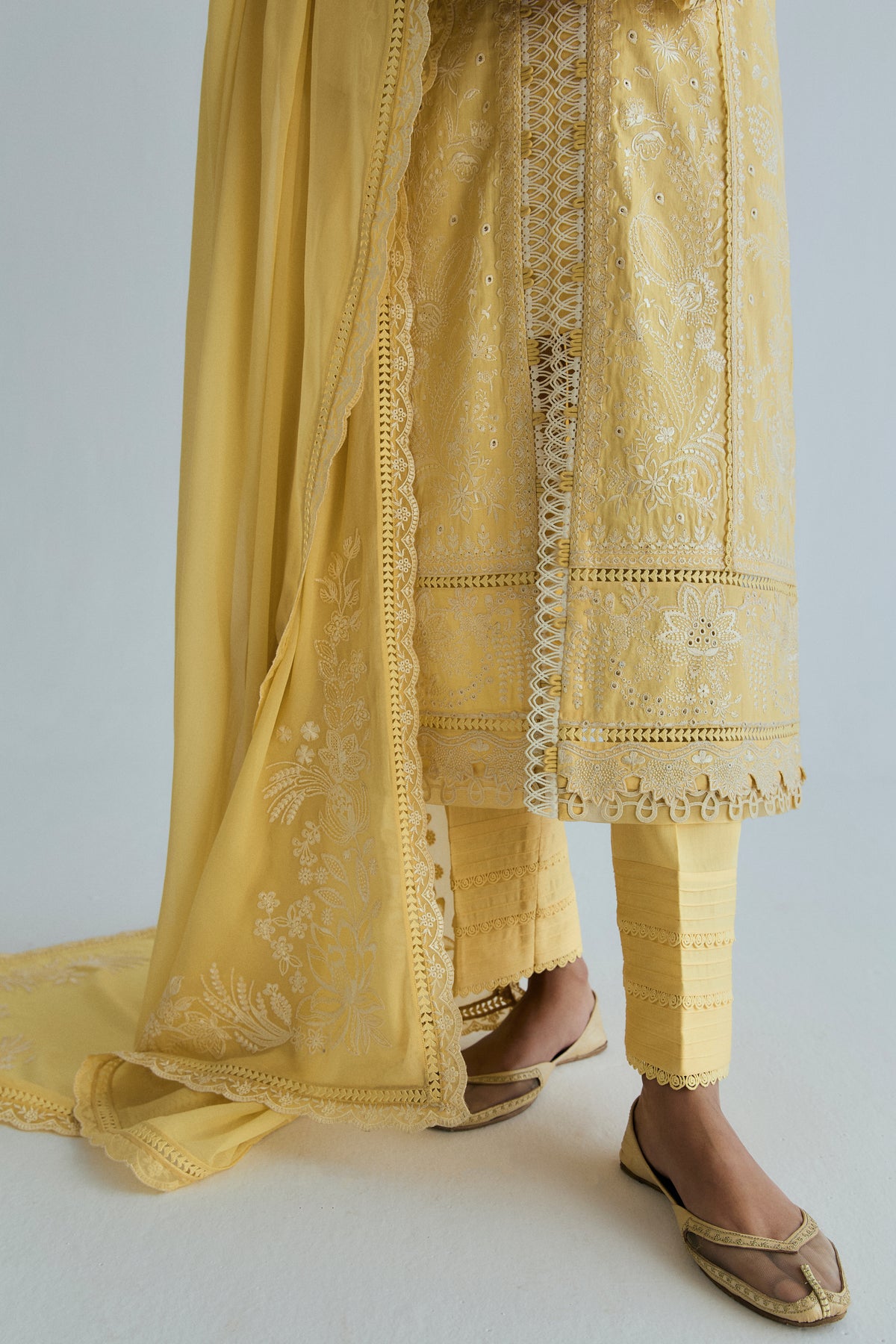 Embroidered kameez hem, pin-tucked trousers with lace cuffs and floral corner of the yellow georgette dupatta